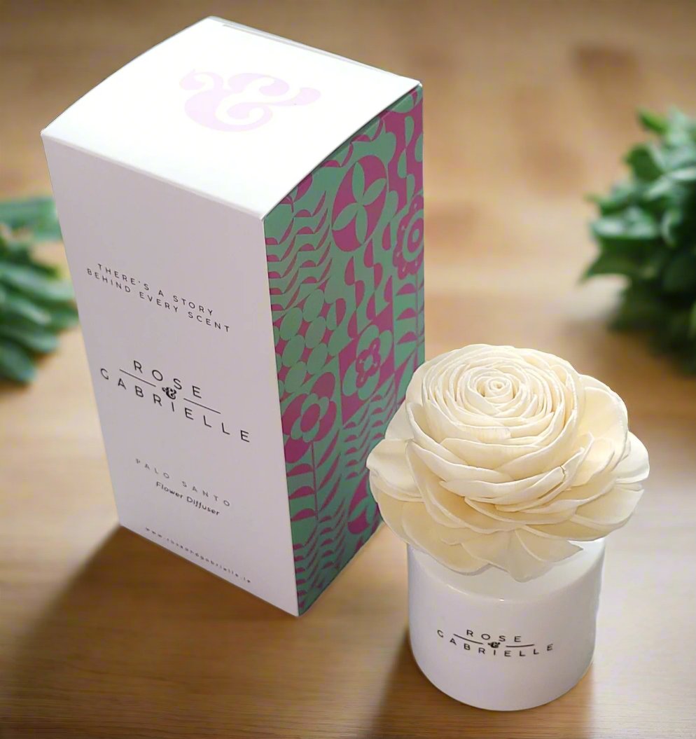 Rose & Gabrielle flower diffuser with a cream sola flower in a white jar beside its patterned box on a wooden table