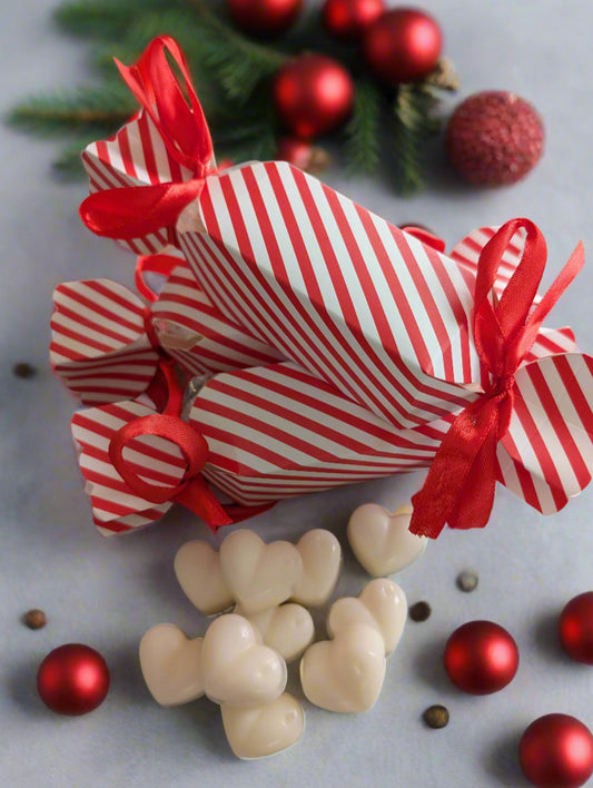 Red and white striped candy canes with red ribbons on a gray surface with Christmas decorations.